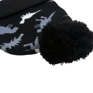 Detailed view of kids dinosaur knit hat featuring grey patterns and a large black pompom
