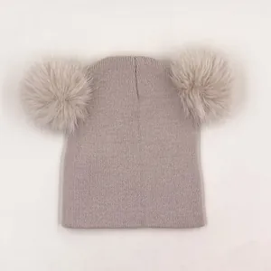 Détail du bonnet en maille côtelée pour enfant avec deux grands pompons en fourrure