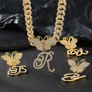 Detail of gold Cuban chain necklace with iced-out butterfly and crystal letter pendants