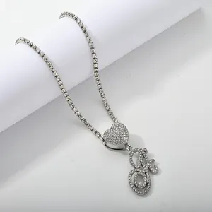 Macro detail of silver tennis chain necklace with iced-out heart and letter B pendant