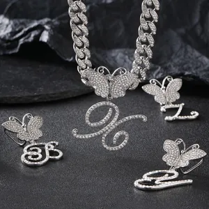 Macro view of iced out silver Cuban link chain with crystal butterfly and cursive letter G B Z