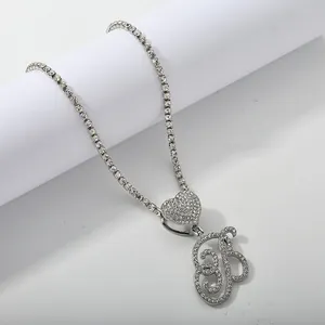 Macro shot of silver tennis chain with iced out heart and cursive letter B pendant