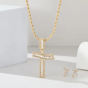 Dettaglio del set di gioielli con ciondolo lettera T dorato e orecchini con zirconi cubici