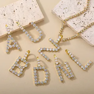 Detail van vergulde alfabet hangers met sprankelende pavé kristallen op stenen ondergrond
