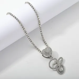 Macro detail of silver tennis chain with heart clasp and iced out letter H pendant