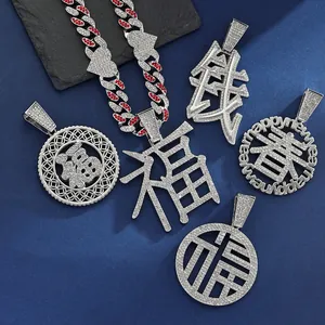 Flat lay of iced-out hip-hop pendants with Fu, Qian, and Chun characters on blue background