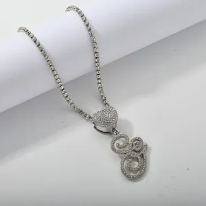 Detailed macro of a silver-tone tennis chain necklace with a crystal heart and G pendant