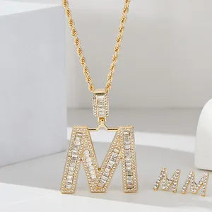 Dettaglio del set collana e orecchini a lettera M dorata con zirconi cubici luminosi