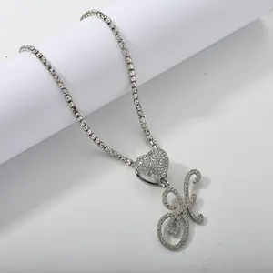 Macro detail of silver tennis chain with heart pendant and iced out letter K charm