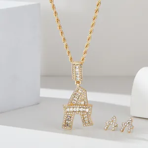 Dettaglio parure hip-hop dorata lettera A con ciondolo e orecchini in diamanti baguette