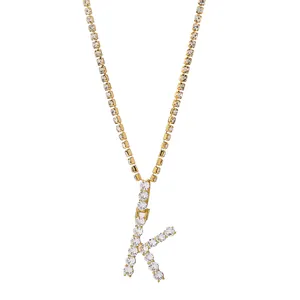 Detail van een vergulde letter K hanger met tennisketting en pavé gezette kristallen