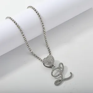 Macro detail of silver tennis chain with heart and cursive letter L pendant and zircons