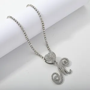 Detailed view of silver tennis chain with iced-out heart and cursive letter M pendant
