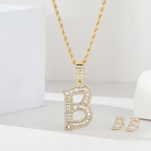 Dettaglio del set di gioielli con lettera B dorata e strass scintillanti baguette e tondi