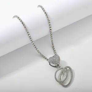 Macro detail of silver tennis chain with heart clasp and iced out letter D pendant