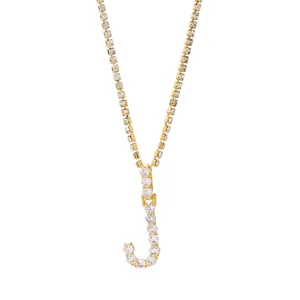 Detail van gouden letter J hanger met zirkonia steentjes aan een elegante tennis ketting