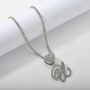 Macro detail of silver hip hop tennis chain with iced out heart and cursive letter pendant