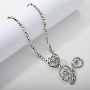 Close-up of sparkling silver tennis chain with heart pendant and iced out script initial
