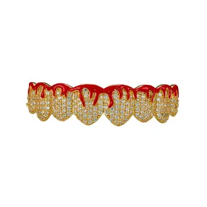 Close-up of hip hop gold grillz with red drip design and white cubic zirconia stones