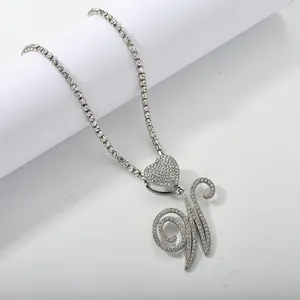 Macro view of silver heart pendant with iced out cursive letter N on tennis chain