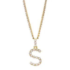 Detailopname van gouden tennisketting met een grote S-vormige hanger bezet met zirkonia steentjes