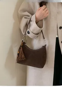 Detail of dark brown matte crescent hobo bag with tassel and beads on wool coat