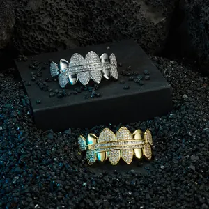 Hip hop style gold and silver fang grillz with full zircon inlay on dark volcanic rock