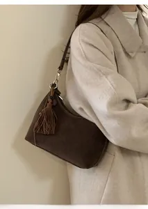 Detail of dark brown suede shoulder bag featuring elegant fringe tassel and zipper closure