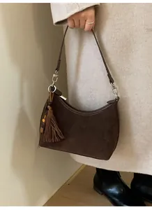 Close-up of brown suede crescent bag featuring side fringe with wooden bead detail