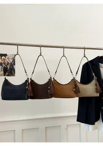Detail view of four hobo bags in suede texture featuring side tassels and wooden beads
