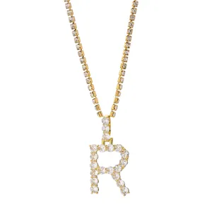 Detail van een hiphop gouden letter R-hanger aan een fonkelende kristallen tennisarmband