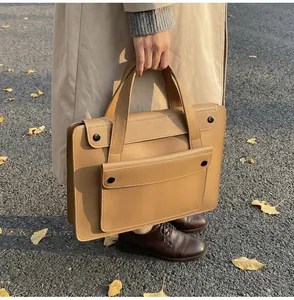 Detail of vintage camel leather laptop bag with double compartments and metal snap buttons