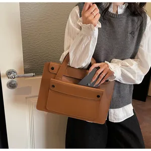 Detail of caramel leather briefcase showing a phone being placed inside the pocket