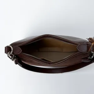 Minimalist dark brown baguette bag with leather and suede splicing, zipper and tassel