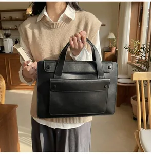 Woman holding black leather briefcase with front double snap pockets in a cozy interior
