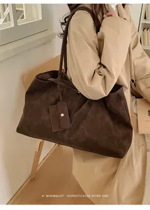 Detail of a large dark brown suede tote bag with a small matching pouch and metal clasp