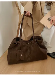 Detail of dark brown matte leather tote bag featuring a detachable mini buckle pouch