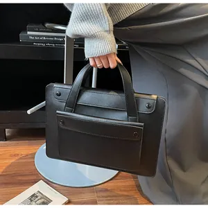 Close-up of black waterproof business tote bag featuring a snap button front pocket detail