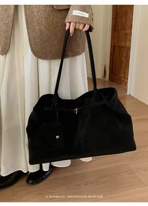 Detail of minimalist black matte tote bag with silver buckle and matching mini pouch