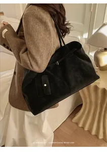 Detail view of a large black suede tote bag with slim shoulder straps for daily commute