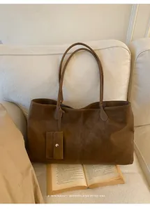 Detail of retro brown tote bag on sofa featuring matching detachable card holder accessory