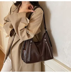 Détail du sac hobo marron foncé avec fermetures éclair à pompons et cuir lisse brillant