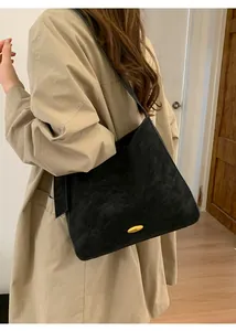 Minimalist black matte shoulder bag with gold metal buckle detail on a model