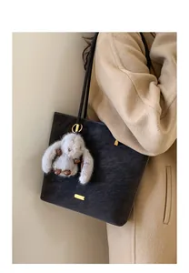 Details der großen schwarzen Vintage-Beuteltasche mit Plüschhasen-Anhänger und Goldplatte
