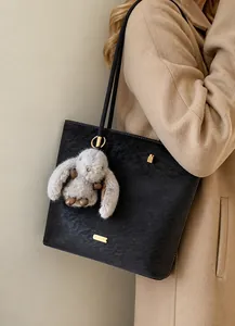 Detailansicht der Wildleder-Beuteltasche mit Goldbeschlägen und Plüschhasen-Anhänger