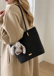 Detail der dunkelgrauen Beuteltasche mit Plüschhasen-Anhänger und goldenen Beschlägen