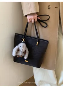 Detail der schwarzen Bucket Bag aus Kunstfell mit goldenen Beschlägen und Hasen-Anhänger