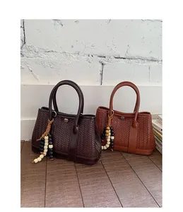 Detail van geweven crossbodytassen in koffie en bruin met decoratieve houten kralen