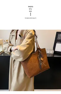 Dettaglio borsa tote marrone vintage con ciondoli decorativi indossata da una modella