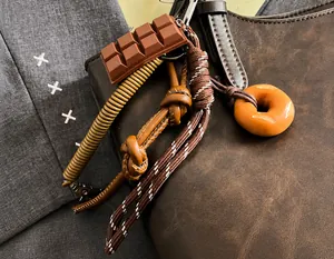Dettaglio della borsa tote in pelle marrone scuro con ciondoli a forma di cioccolato